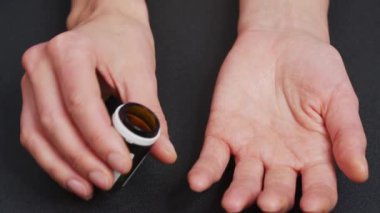 Büyük silindirik haplar ilaç şişesinden avuç içine düşer. Yakın çekim, ön görüntü, merkez kompozisyon.