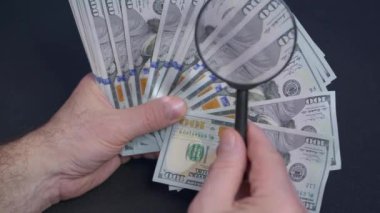 Bir kişi büyüteçle dolar banknotunu kontrol ediyor, kapatın..