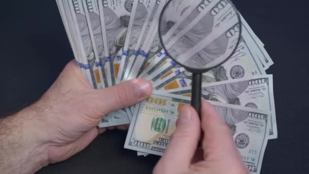 Person som kontrollerar dollarsedeln för äkthet med förstoringsglas, närbild. — Stockvideo
