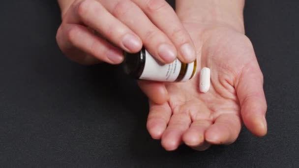 Due grandi pillole rotonde bianche cadono nel palmo della mano dalla bottiglia della pillola. Primo piano, vista frontale, composizione centrale. — Video Stock