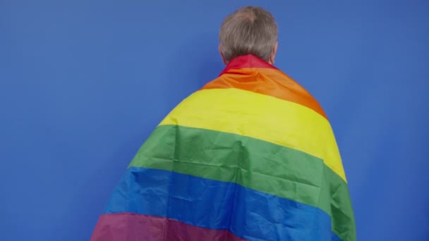 Orang tua memegang dengan bendera kebanggaan lgbt. Sendirian. Satu. menutupi bendera LGBT. Bendera LGBT pada latar belakang biru. — Stok Video
