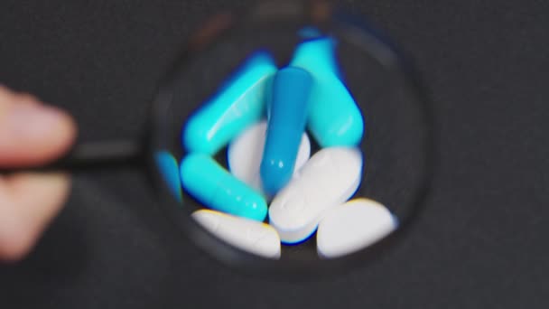 Schauen Sie durch eine Lupe Schmerztabletten, Antibiotika-Tabletten, Schwellungen Pille und Kalzium Tablette. Schmerztabletten - Apotheke und Behandlungskonzept. — Stockvideo