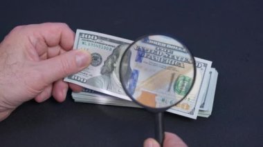 Bir kişi büyüteçle dolar banknotunu kontrol ediyor, kapatın..