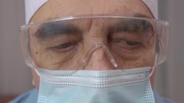 Retrato de cerca del cansado médico exhausto con máscara y auriculares después del turno duro y tratando a los pacientes en el hospital o clínica. Concepto de medicina. — Vídeos de Stock