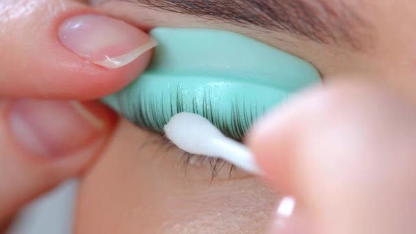 Gesicht eines jungen Mädchens vor einem modernen Wimpernkaschierungsverfahren in einem professionellen Schönheitssalon. Der Meister trägt vor dem Wimpernkräuseln einen speziellen Kleber auf. — Stockvideo