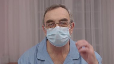 Yakın plan portre yaşlı bir adam tıbbi maskesini çıkartıyor..