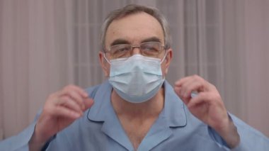 Yakın plan portre yaşlı bir adam tıbbi maskesini çıkartıyor..