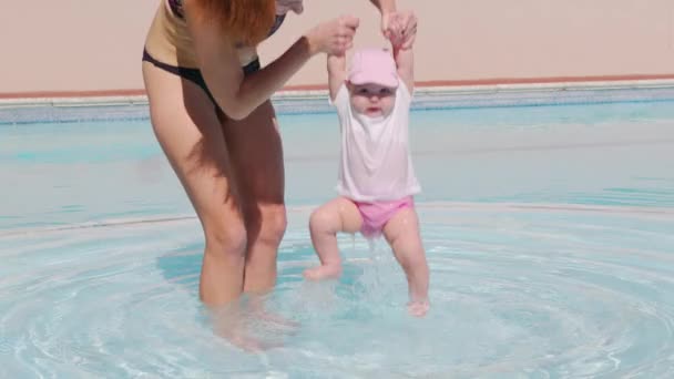 Egy anya és egy baba egy szabadtéri medencében. Anya megcsókolta a kisbabát az uszodában. Anya átöleli gazdaság és gondoskodás csecsemő. — Stock videók