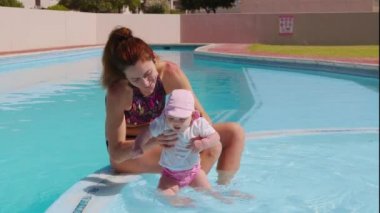 Annesiyle yüzme havuzunda yürüyen mutlu bir kız..