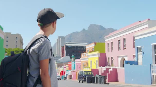 Menino turista na cidade do Cabo Bo-Kaap área malaia, perspectiva de rua de pedra calçada, casas de terraço coloridas, lavanderia no lado da linha de casa. — Vídeo de Stock