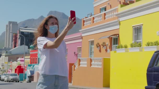 Vrouw toerist in pandemie schiet aan de telefoon in Kaapstad Bo-Kaap Malay gebied, perspectief van kasseien straat, gekleurde terrassen huizen, Zuid-Afrika. — Stockvideo