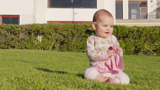 Retrato de menina. Adorável jogar ao ar livre olhando para a câmera sorrir 9 meses feliz bebê jogando. Adorável bebê menina sentar na grama. — Vídeo de Stock