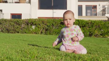 Çimlerin üzerinde oynayan küçük bir kızın portresi..