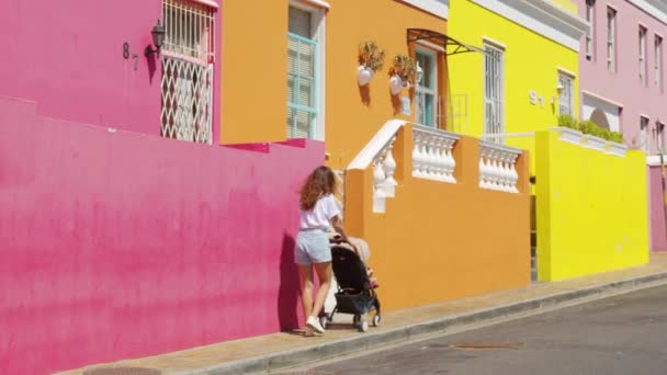 Γυναίκα περπάτημα με καροτσάκι μωρό στους δρόμους των πολύχρωμων κτιρίων γειτονιά Bo-Kaap Cape Town Νότια Αφρική. — Αρχείο Βίντεο