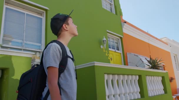Menino turista na cidade do Cabo Bo-Kaap área malaia, perspectiva de rua de pedra calçada, casas de terraço coloridas, lavanderia no lado da linha de casa. — Vídeo de Stock