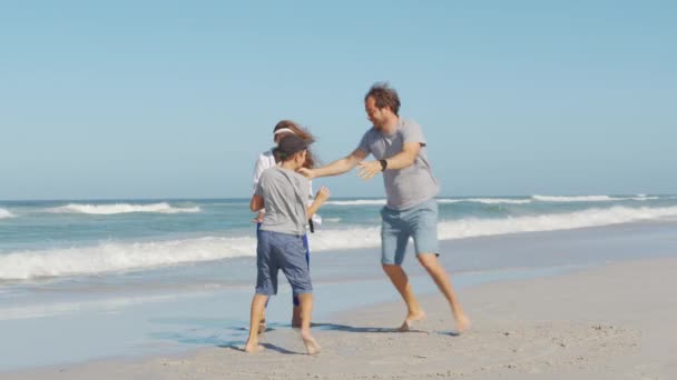 Jovem família feliz desfrutar de férias no oceano de praia. Pai, mãe e filho relaxam andando juntos perto do oceano. — Vídeo de Stock