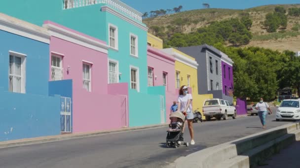 Mulher caminhando com carrinho de bebê nas ruas de edifícios coloridos bairro Bo-Kaap Cidade do Cabo África do Sul. — Vídeo de Stock