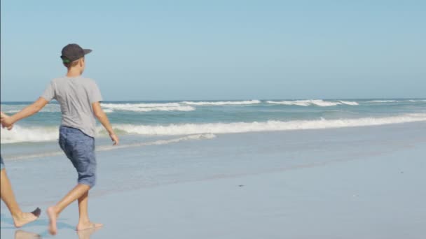 Jovem família feliz desfrutar de férias no oceano de praia. Pai, mãe e filho relaxam andando juntos perto do oceano. — Vídeo de Stock