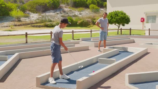 Homme avec son fils jouant aux mini-golfeurs sur un terrain de mini-golf le jour d'été. — Video