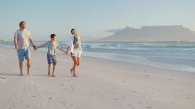 Mutlu aile gün batımında sahilde yürür. Anne, baba ve bebek gün batımında mutlu yürüyüşler. Ortak aile sağlıklı bir yaşam tarzı yürür. Mutlu aile ve aile değerleri kavramı.