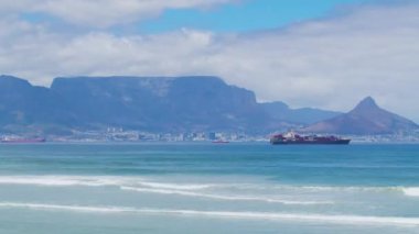 Güzel, açık bir gün. Masa dağına bakıyorum. Okyanus dalgaları kayalık kıyı şeridine çarpıyor..