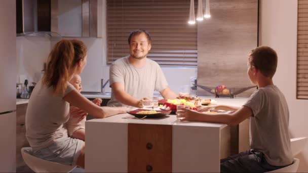 台所で:一緒に夕食を持って4人の家族.お母さん、お父さん、男の子と女の子は自宅でごちそうを楽しんで. — ストック動画