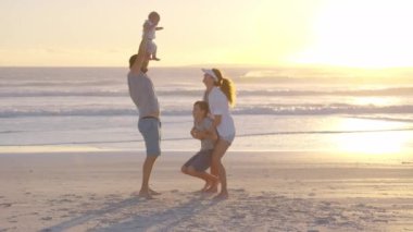 Mutlu bir aile gün batımında sahilde oynuyor ve eğleniyor. Ağır çekim. Aile, Özgürlük ve Seyahat konsepti.