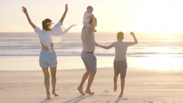 Mutlu aile gün batımında sahilde yürür. Anne, baba ve bebek gün batımında mutlu yürüyüşler. Ortak aile sağlıklı bir yaşam tarzı yürür. Mutlu aile ve aile değerleri kavramı. — Stok video