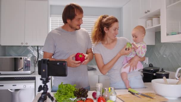 Весела сім'я з дитячим обідом. Портрет радісної кавказької родини блогерів, які готують їжу вдома на кухні. Сучасні технології та блог. — стокове відео