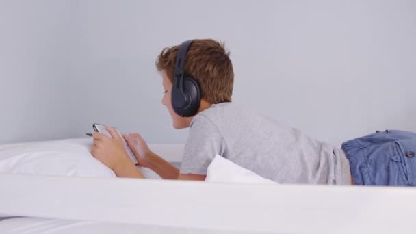 Teenager mit Kopfhörern hören Musik, während Sie im Zimmer auf das Tablet schauen. — Stockvideo