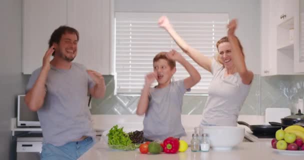 Grappig gelukkig gezin en leuke kinderen hebben plezier dansen in de keuken samen, actieve moeder vader genieten funky dans met zoon. — Stockvideo