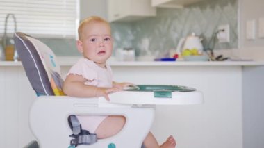 Funny toddler sitting in baby chair and crying.