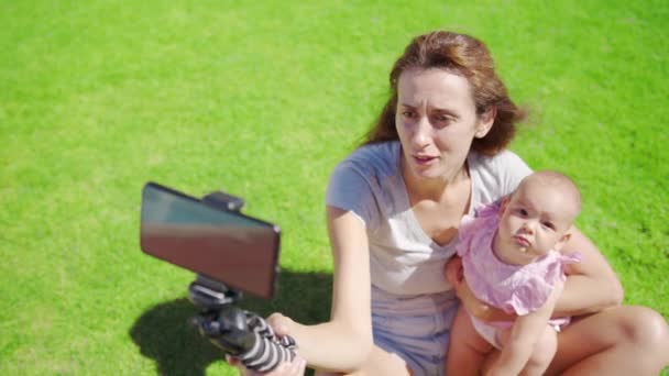 Madre blogger con figlioletta divertirsi registra un video blog su erba verde. — Video Stock