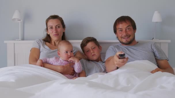 ครอบครัวยุโรปที่มีความสุขกับเด็กสองคนรวมตัวกันบนโซฟาเพื่อดูทีวีในห้องยิ้ม ความร่วมมือและความบันเทิง . — วีดีโอสต็อก