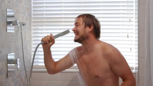 Щасливий молодий чоловік співає, приймаючи ранковий душ. Усміхнений бородатий м'язистий чоловік миє під теплою водою слухаючи музику, насолоджуючись гігієнічною рутиною у ванній . — стокове відео