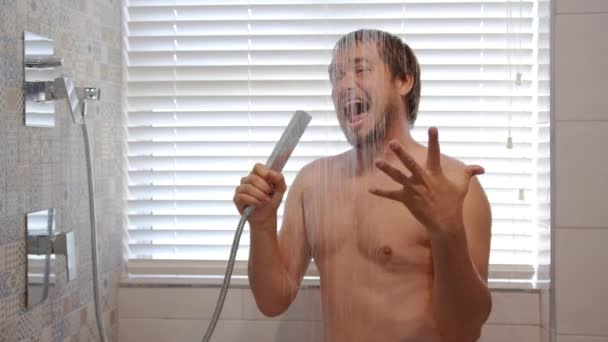 Glad ung man som sjunger i morgonduschen. Le skäggig muskulös man tvätta under varmt vatten lyssna musik njuter hygien rutin i badrummet. — Stockvideo