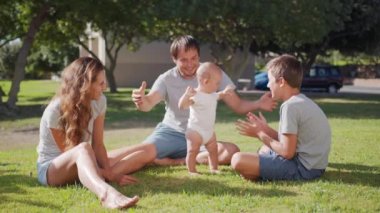 Bebek çimenlerde ilk adımı atıyor. Aile kızıyla birlikte doğa çocuğunun hayalindeki gibi yürür. Bebek annesiyle ilk adımı atıyor. Mutlu bir aile..