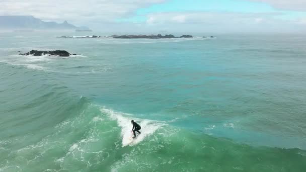 空中撮影:男性サーファーがキャッチし、大規模なバレリング波に乗る。大きな波の上でバランスをとるサーファーのドローン追跡映像。極端なウォータースポーツ. — ストック動画