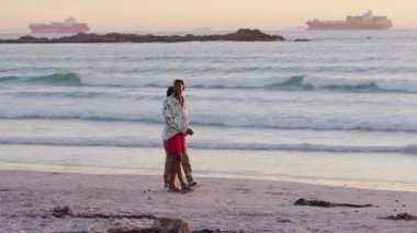 Güney Afrika, Cape Town, Nisan 04, 2021 Siyahi adam birbirine sevgiyle sarılıyor. Okyanusta güzel bir çift, gün batımı