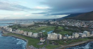 Arka planda Masa Dağı 'nın olduğu muhteşem bir günbatımında Cape Town' a doğru ilerleyen geniş bir hava görüntüsü..