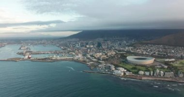 Arka planda Masa Dağı 'nın olduğu muhteşem bir günbatımında Cape Town' a doğru ilerleyen geniş bir hava görüntüsü..