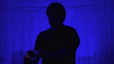 Mavi arka plandaki büyücü önünde yanan bir el tutuyor. Sihirbaz, kamerada ateş elementi gösterir. Önünde yanan bir el..