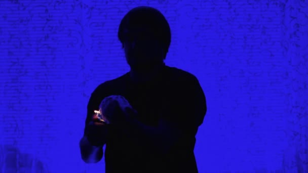 青い背景のウィザードは彼の前で燃える手を保持しています。魔術師はカメラの火の要素を示しています,前の人の燃える手. — ストック動画