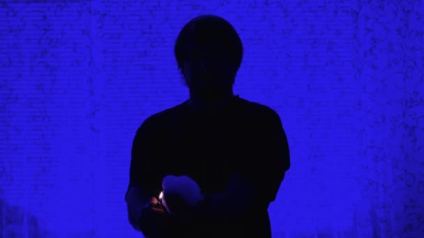 Trollkarl på blå bakgrund håller en brinnande hand framför sig. Magikern visar elementet i kameran, den brinnande handen på en person framför. — Stockvideo