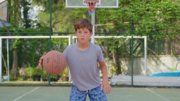 Pojke tränar på att spela basket utomhus. — Stockvideo