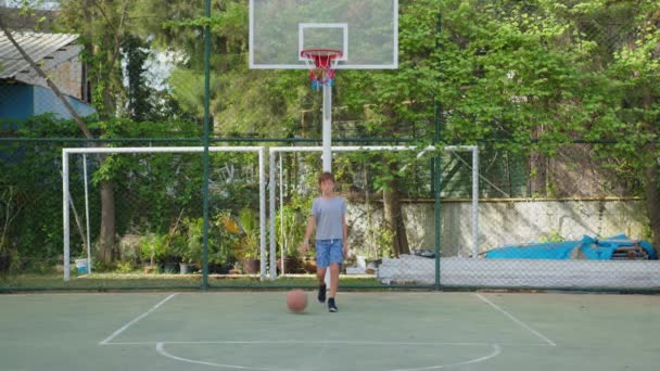 Garçon pratiquant un basketball en plein air. — Video