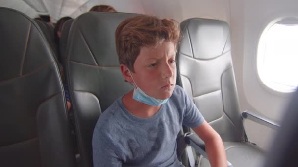 Chłopiec podróżnik latający samolotem w środku w masce. Wybuch epidemii wirusa, koncepcja pandemii podróżujących pasażerów. Lot turystyczny. — Wideo stockowe