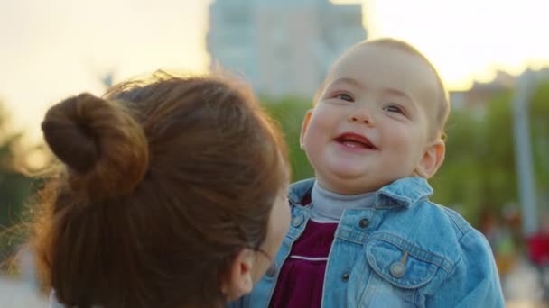 Glücklich lächelnde Mutter hält ihr Kleinkind in den Armen und hat Spaß sie lachen. Nahaufnahme. — Stockvideo