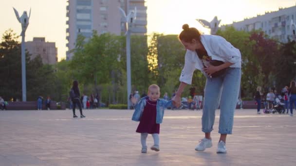 Det lilla barnet lär sig att gå. Första steget. Föräldrar lär sitt barn att göra de första stegen på ett grönt gräs på sommaren. Glad barndom och föräldraskap koncept. Familjekärlek. — Stockvideo