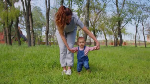 Baby erster Schritt im Freien gehen. Mutter hilft ihrem Baby beim ersten Schritt in den Park. — Stockvideo